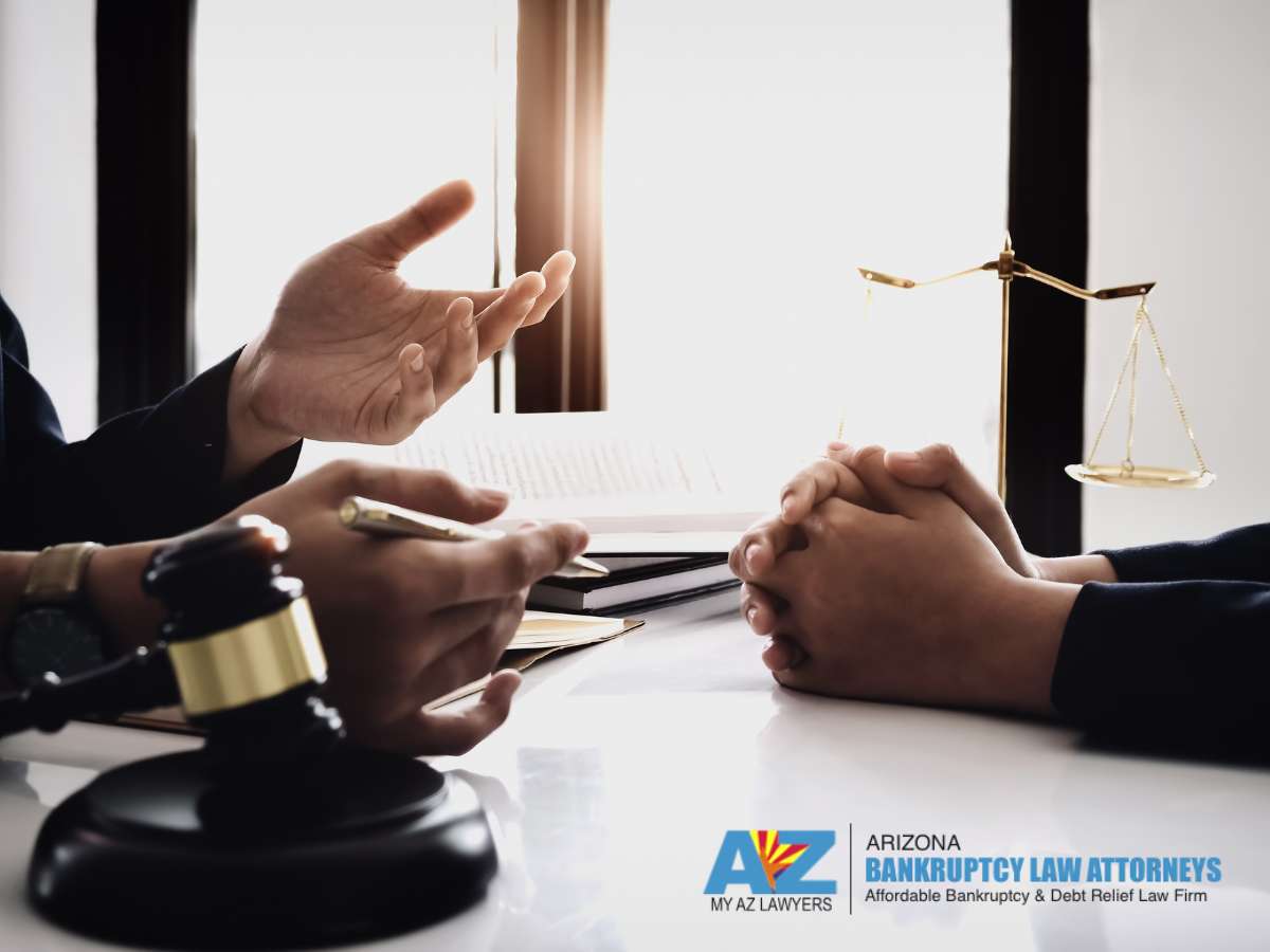 An Arizona bankruptcy attorney discusses options with a client in a consultation room, with a gavel and scales of justice in the background